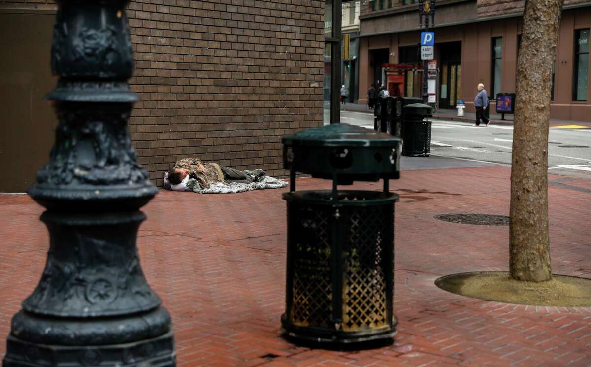 A homeless man rests on Market Street in March 2020.