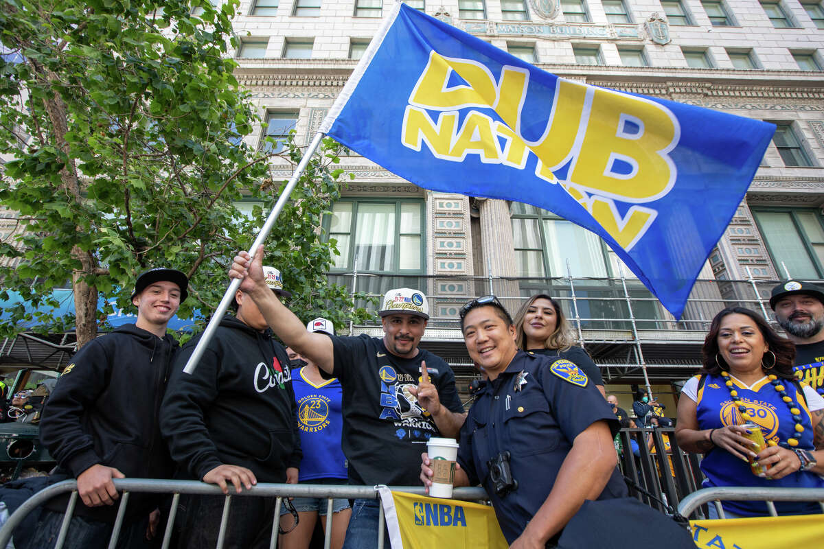 A fan holds the Dub Nation flag during the Golden State Warriors Championship display on Market Street in San Francisco, California.  On June 20, 2022.