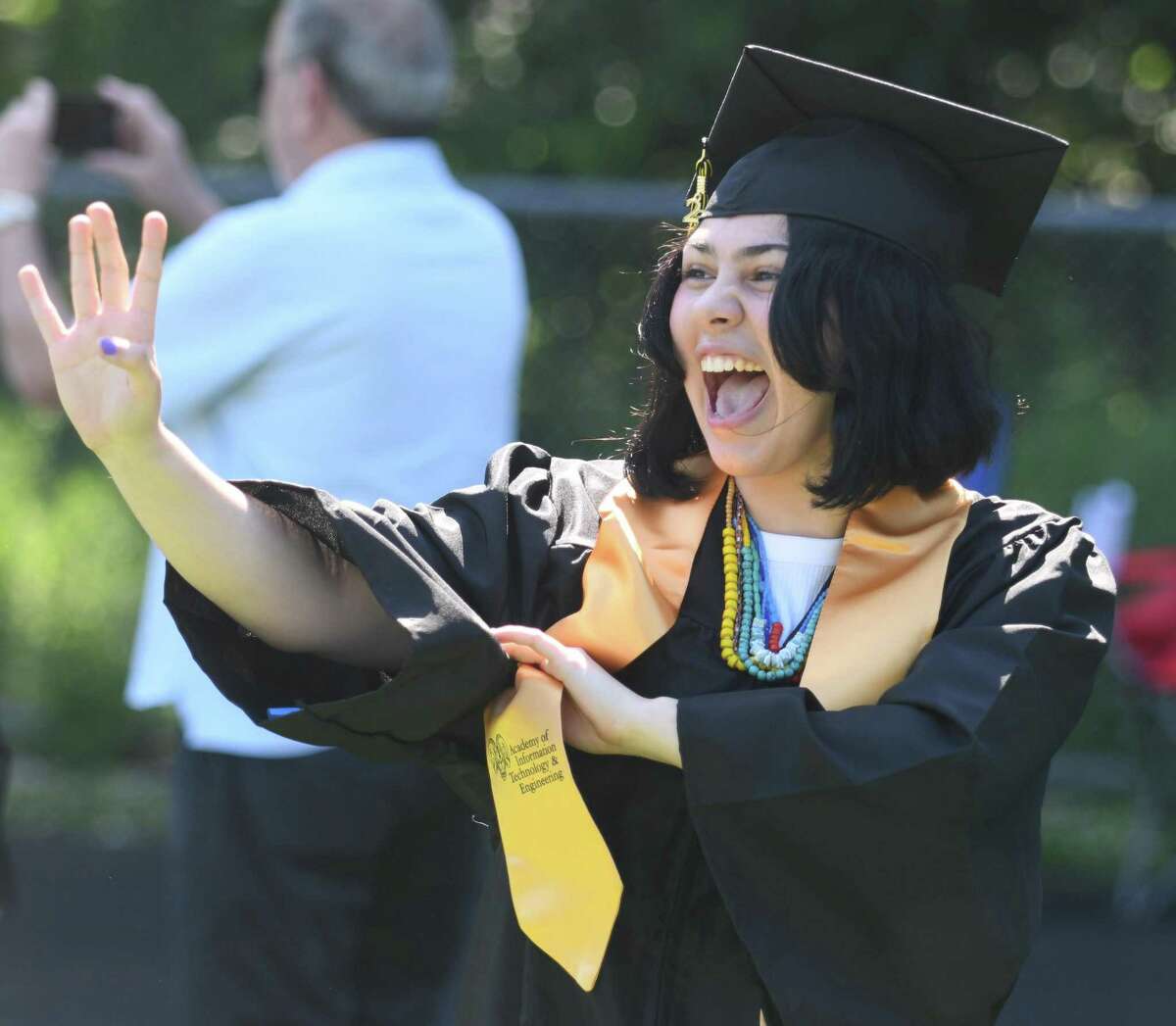 Graduating senior Evyn Christiansen waves to her family during the processional at the 2022 commencement ceremony at Academy of Information Technology & Engineering magnet high school in Stamford, Conn. Monday, June 20, 2022.
