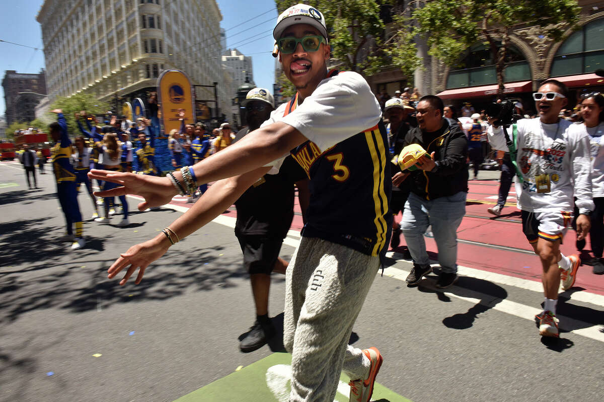 La estrella de los Warriors, Jordan Poole, cruza Market Street para estrechar la mano de los espectadores mientras la ruta del desfile comienza a llenarse de fanáticos que rompieron las barricadas.  