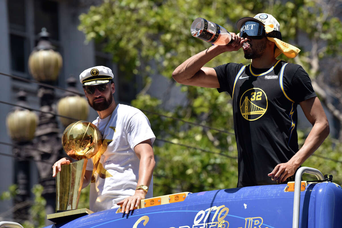 Otto Porter Jr., right, takes a drink of Moët champagne as he proceeds down Market Street with Klay Thompson, during the Warriors victory parade, on Monday June 20, 2022. 