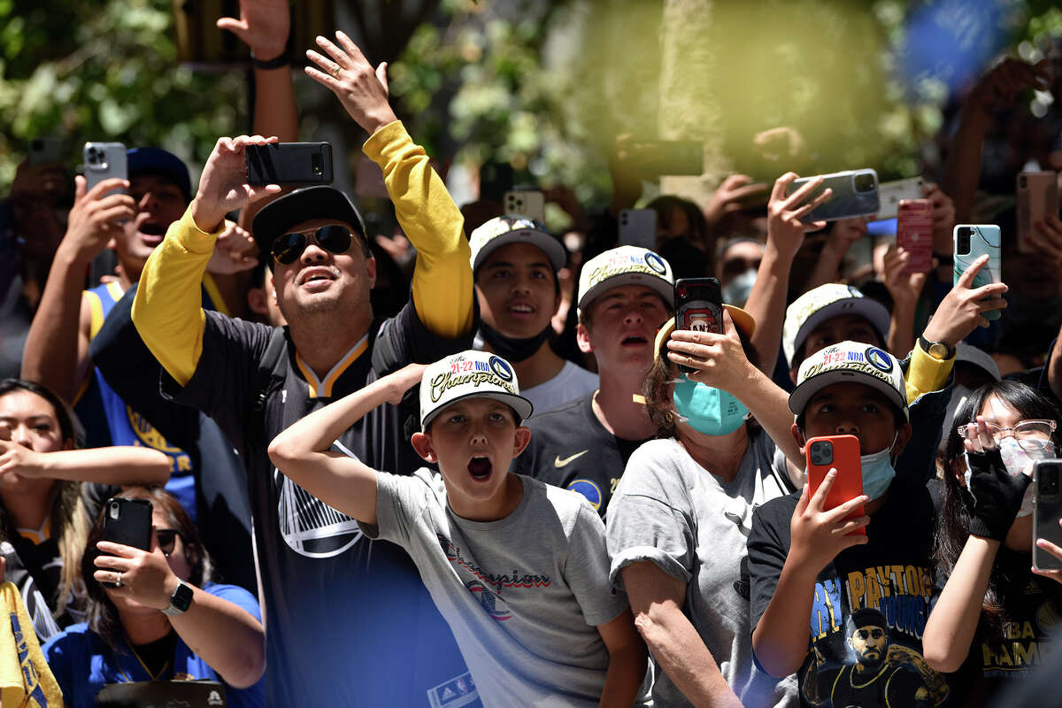Fans react to Stephen Curry as his bus passes them during the Warriors victory parade on Market Street. 
