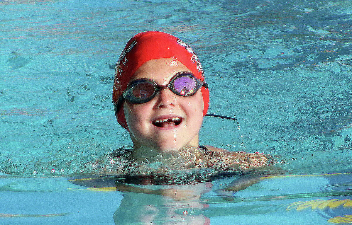 Anna Worman of Montclaire is all smiles as she swims the breaststroke in the girls 8-and-under individual medley Monday during the SWISA Relays at Sunset Hills Country Club.