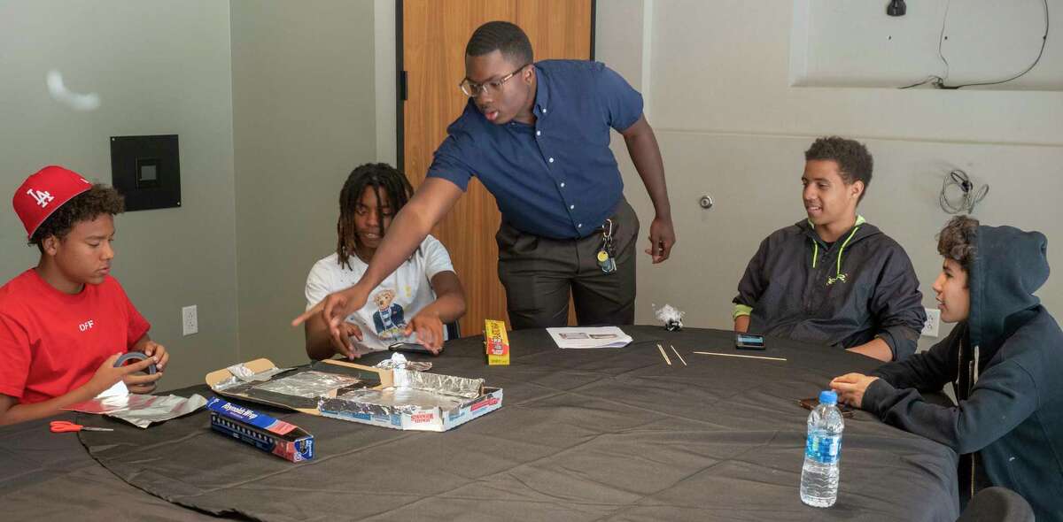 Kelby Smith, facilities intern at Diamondback Energy, works with students from Opportunity Tribe as they make solar powered smores ovens from pizza boxes 06/21/2022 at Diamondback Energy summer STEM Camp at their Fasken Center offices. Tim Fischer/Reporter-Telegram