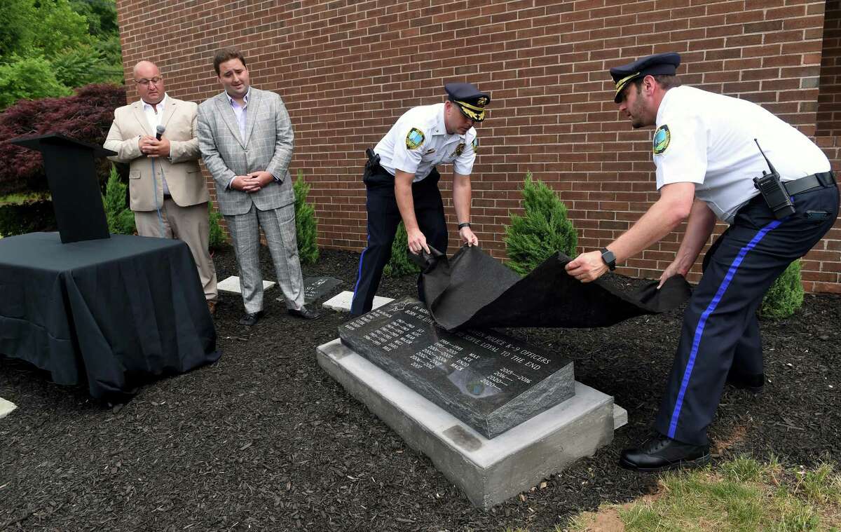 From left, East Haven Memorial Funeral Home owners Joseph Deko and James Integlia watch East Haven Deputy Chief of Police Patrick Tracy and Capt. David Emerman unveil a memorial stone honoring past and present East Haven K-9 officers during a K-9 Memorial Service at the East Haven Police Department on June 21, 2022. Deko and Integlia donated the memorial stone.