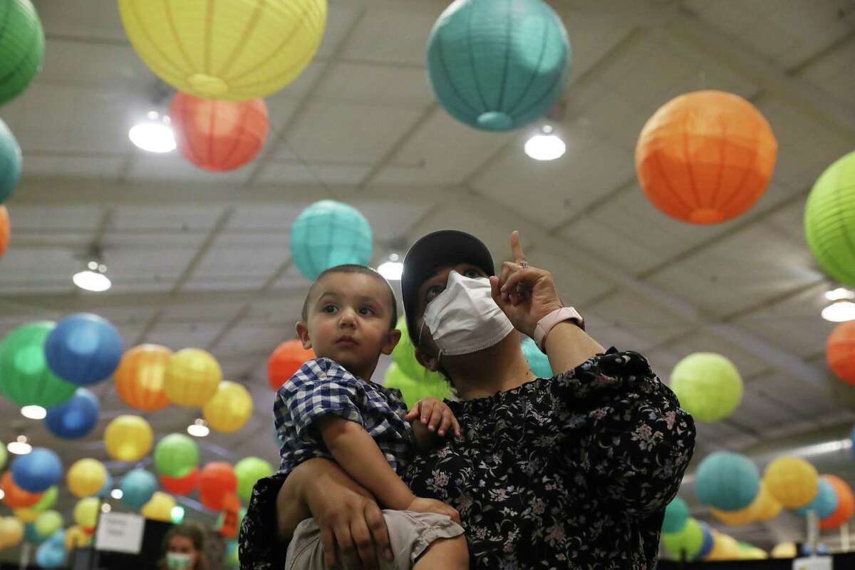 Namraja Nayyar抱着她1岁的儿子Ari Pawra，试图用彩色气球分散他的注意力，然后在加利福尼亚州圣何塞的圣克拉拉县游乐场的一家诊所接种COVID-19疫苗。