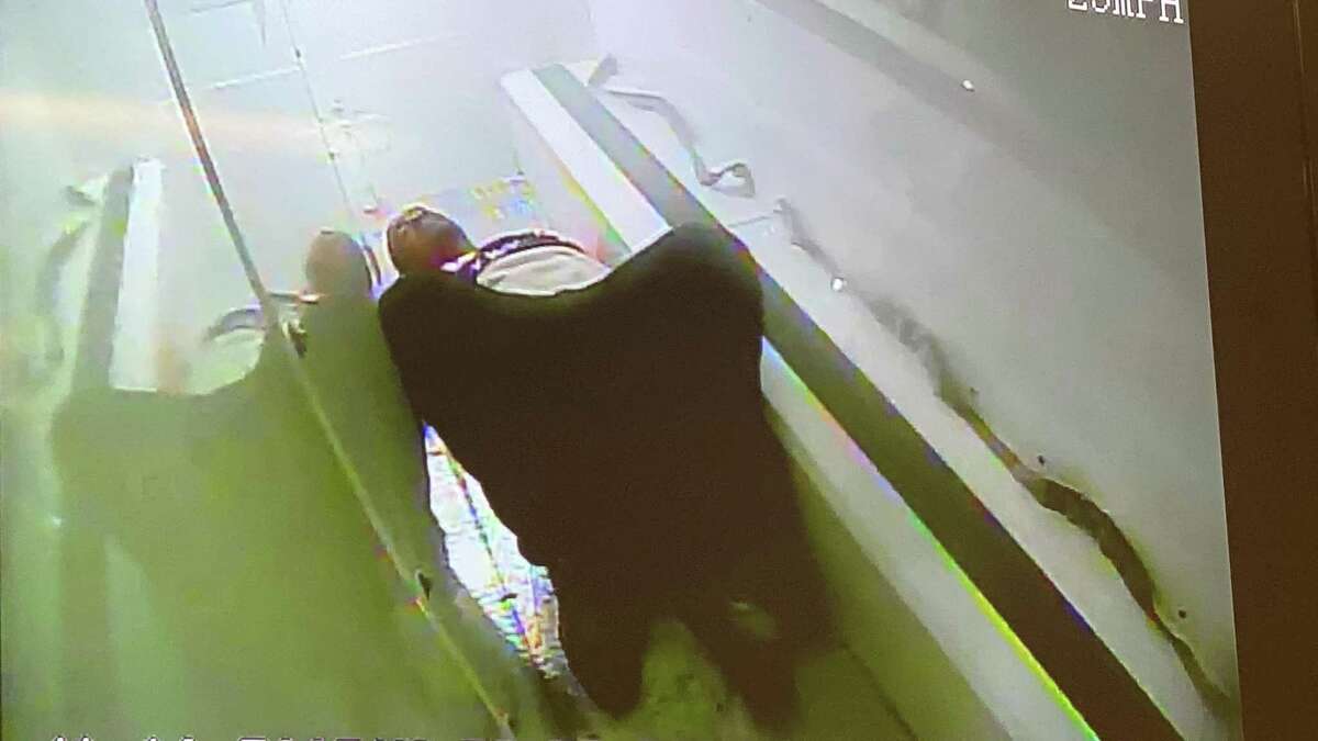 In this still shot taken from police video, Richard Cox is seen lying on the floor of a police van.