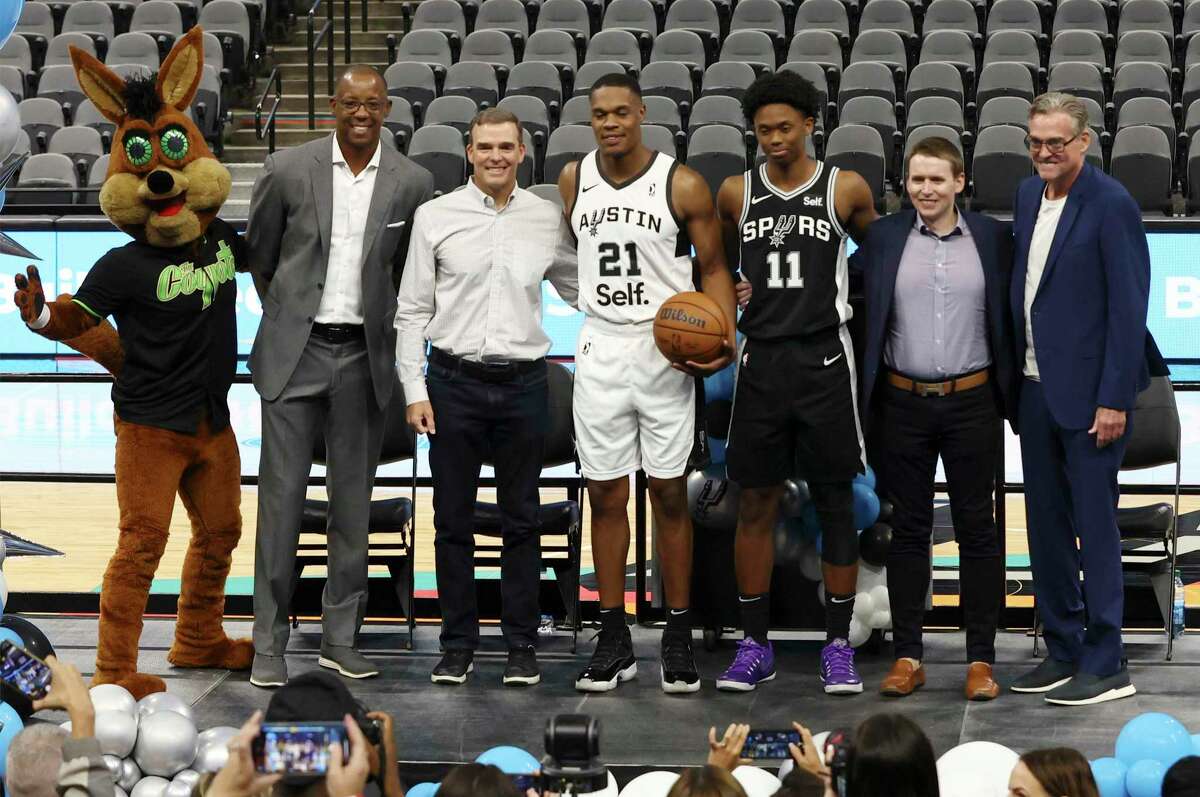 From left, the Spurs Coyote, Sean Elliott, Self Communication Chief Brett Billick, Austin Spurs’ Robert Woodard II, the Spurs’ Josh Primo, Self Financial CEO James Garvey and Spurs CEO R.C. Buford pose after the team announced a new partnership.