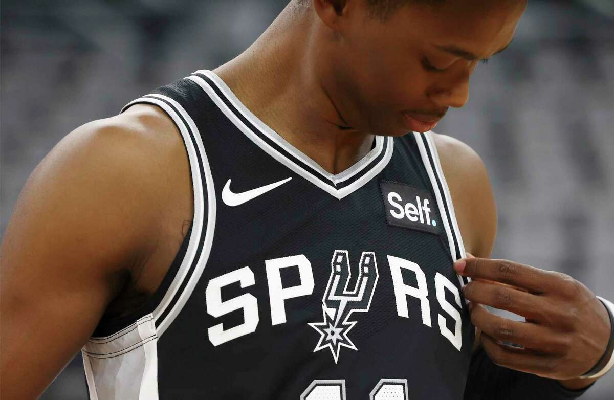 Former Spurs guard Josh Primo looks at the new team logo on a Spurs jersey.  Primo's attorney, William J. Briggs II, said in a statement that his client is. "victim" The former Spurs psychologist has spoken out against her on several occasions. 