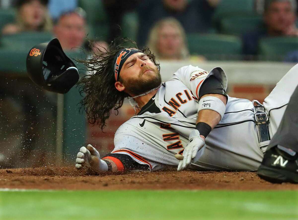 San Francisco Giants shortstop Brandon Crawford loses his helmet crossing home after a tag by Atlanta Braves catcher Travis d' Arnaud during the fourth inning of a baseball game on Tuesday, June 21, 2022, in Atlanta. Crawford was called out on the play but after a review was ruled safe to take a 6-5 lead. (Curtis Compton Atlanta Journal-Constitution via AP)