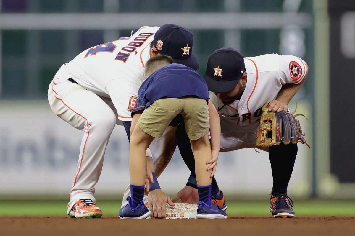 Jose Altuve (right) of the Houston Astros and Mauricio Dubon (left) try to help a young fan that confused which base he was to pick up during a seventh inning Chevy activation in a game between the Houston Astros and the New York Mets at Minute Maid Park on June 21, 2022 in Houston.