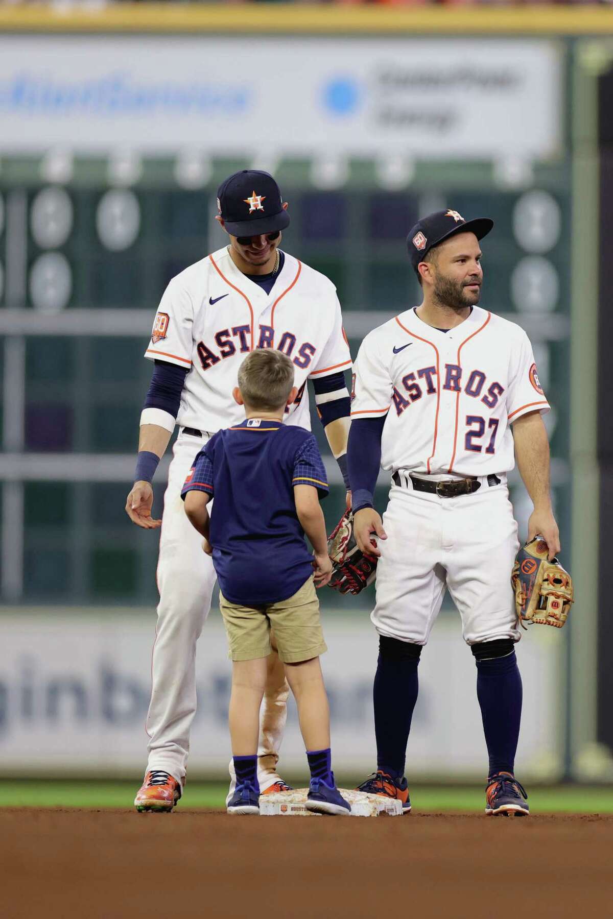 Jose Altuve #27 of the Houston Astros and Mauricio Dubon #14 try to help a young fan that confused which base he was to pick up during a seventh inning Chevy activation in a game between the Houston Astros and the New York Mets at Minute Maid Park on June 21, 2022 in Houston.