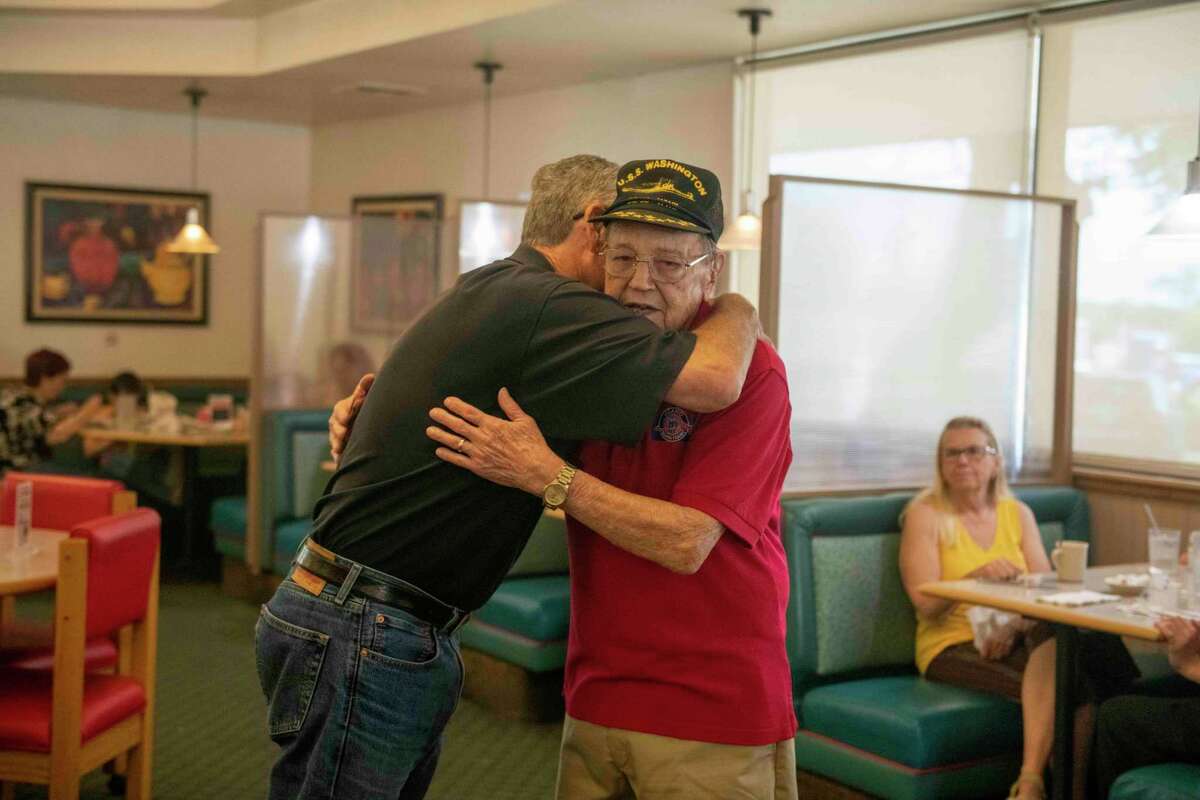 San Antonio native Bill Lozano, 96, gets a hug from Russell Minor at a Jim’s Restaurant in Helotes. Lozano served aboard the battleship USS Washington during the assault on Iwo Jima and other major World War II battles in the Pacific.