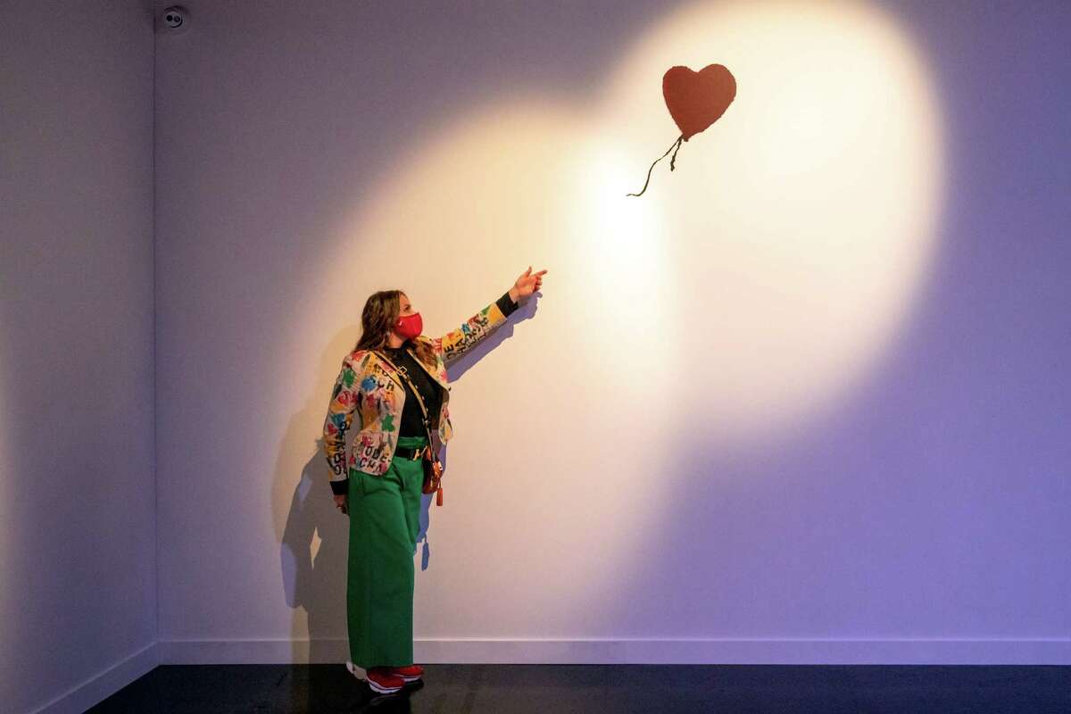 Teresa Rodriguez poses with one of the interactive pieces of artwork at Art of Banksy Unauthorized Private Collection exhibit at the Palace of Fine Arts in San Francisco, Calif. on Nov. 21, 2021.