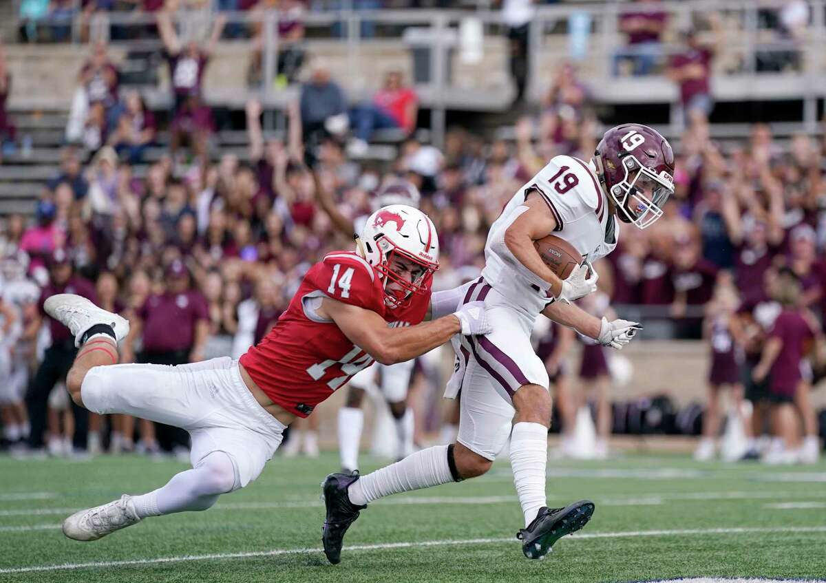 Cinco Ranch wide receiver Noah Abboud (19) scores a touchdown as Memorial defensive back Jake Siblik tries to make the tackle during the first half of a high school football playoff game, Saturday, Nov. 20, 2021, in Houston.