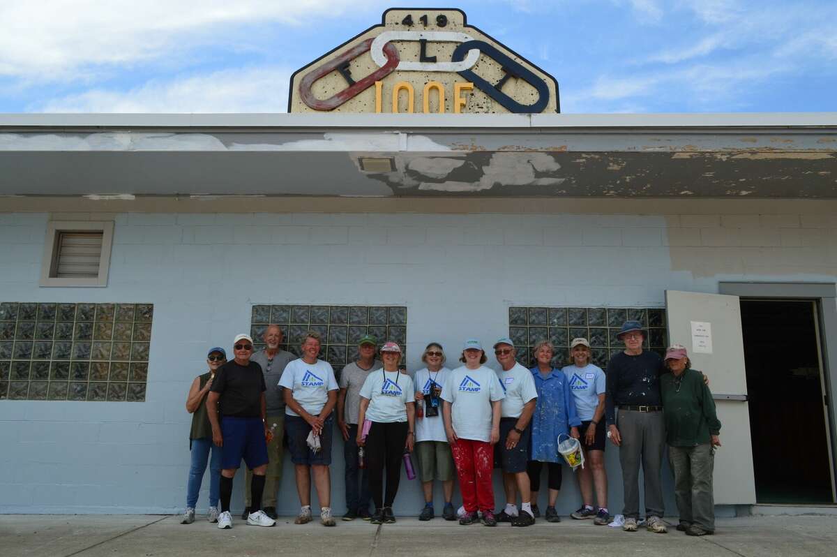 Volunteers with the St. Andrews Mission Project stand in front of the future location of the Whistle Stop Learning Center, in Thompsonville. Volunteers painted the building as art of the project. 