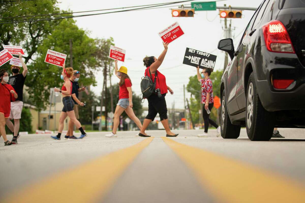 Desiree Alejandro holds up a sign urging people to "Stop TXDOT" while crossing a crosswalk during a demonstration at the intersection of Polk Street and St. Emmanuel Street just east of downtown Houston in 2020.
