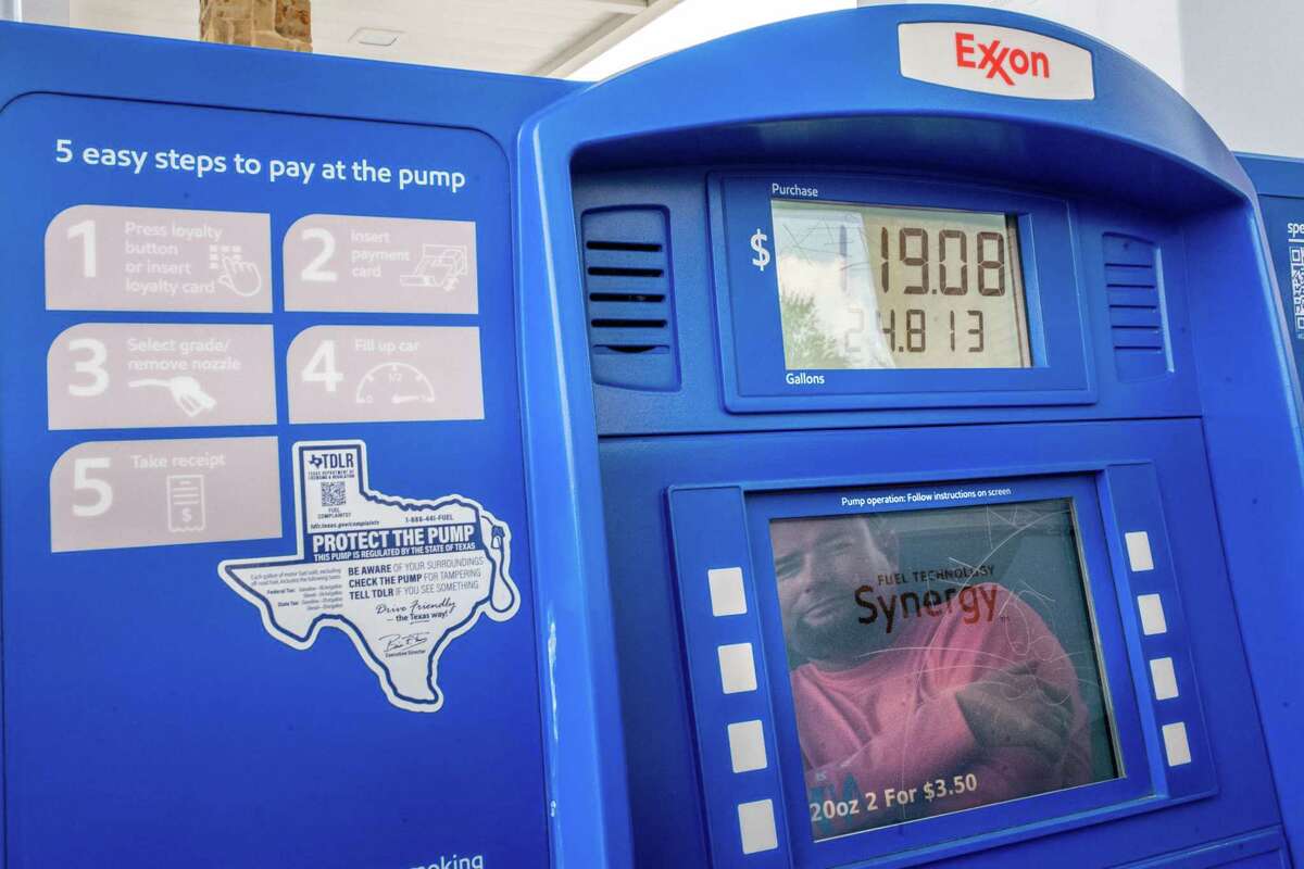 A customer is reflected in a gas pump’s screen while filling up at an Exxon Mobil station in Houston.