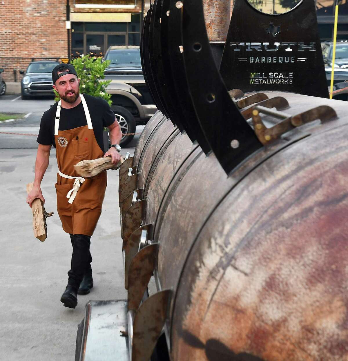 Truth BBQ pitmaster/owner Leonard Botello carries wood to his smoker in the parking lot of Bludorn restaurant Thursday May 12,2022. Botello and Bludorn chef/owner Aaron Bludorn teamed up for an exclusive collaboration dinner benefitting World Central Kitchen at Bludorn Thursday, May 12,2022.