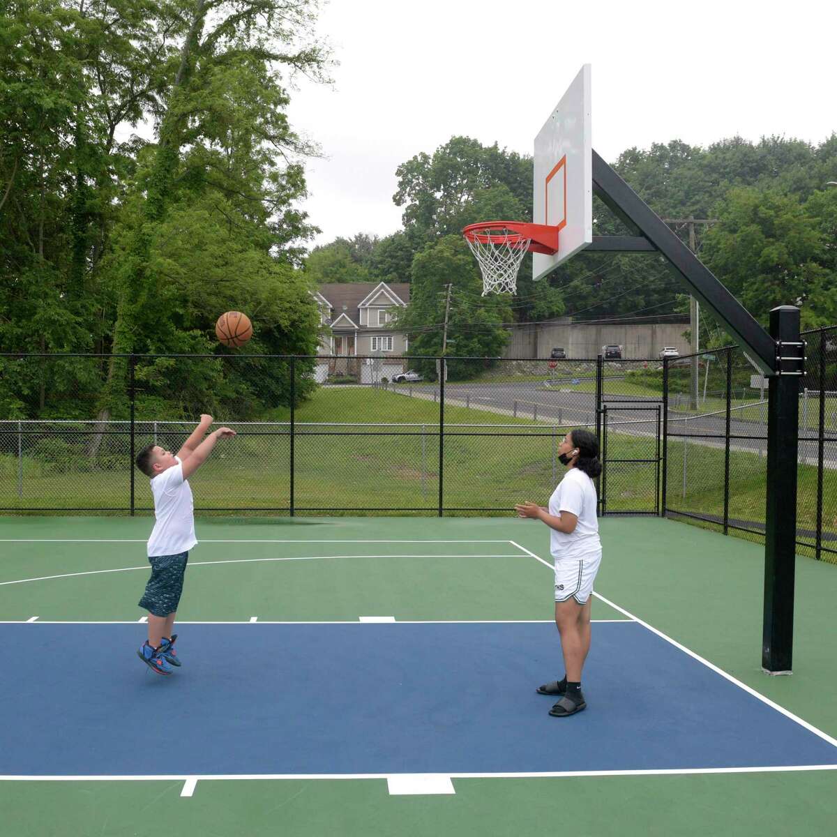 Xiomara Sotro, 15, plays basketball in the rain with her brother Eddie Villalongo, 8, on the new court in Rogers Park. Wednesday, June 22, 2022, Danbury, Conn.