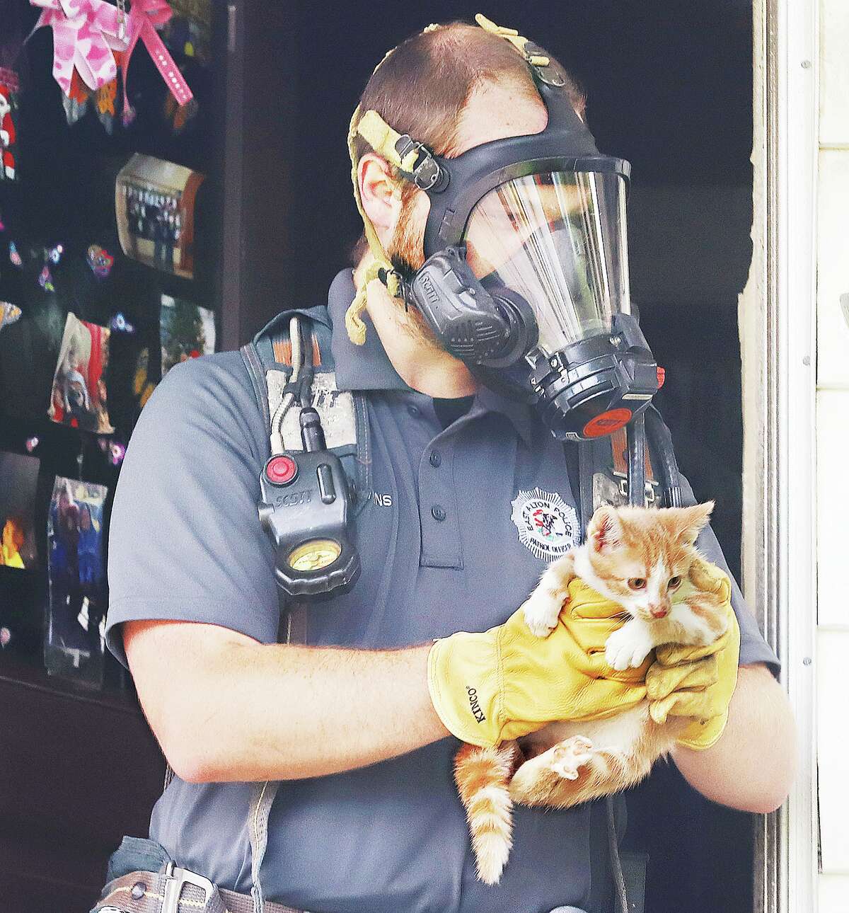 John Badman|The Telegraph An East Alton Police officer, wearing a tank of breathable air, carries out one of many cats from a duplex Wednesday in the 100 block of Ohio Street. The stink from the apartment could be smelled from the street.