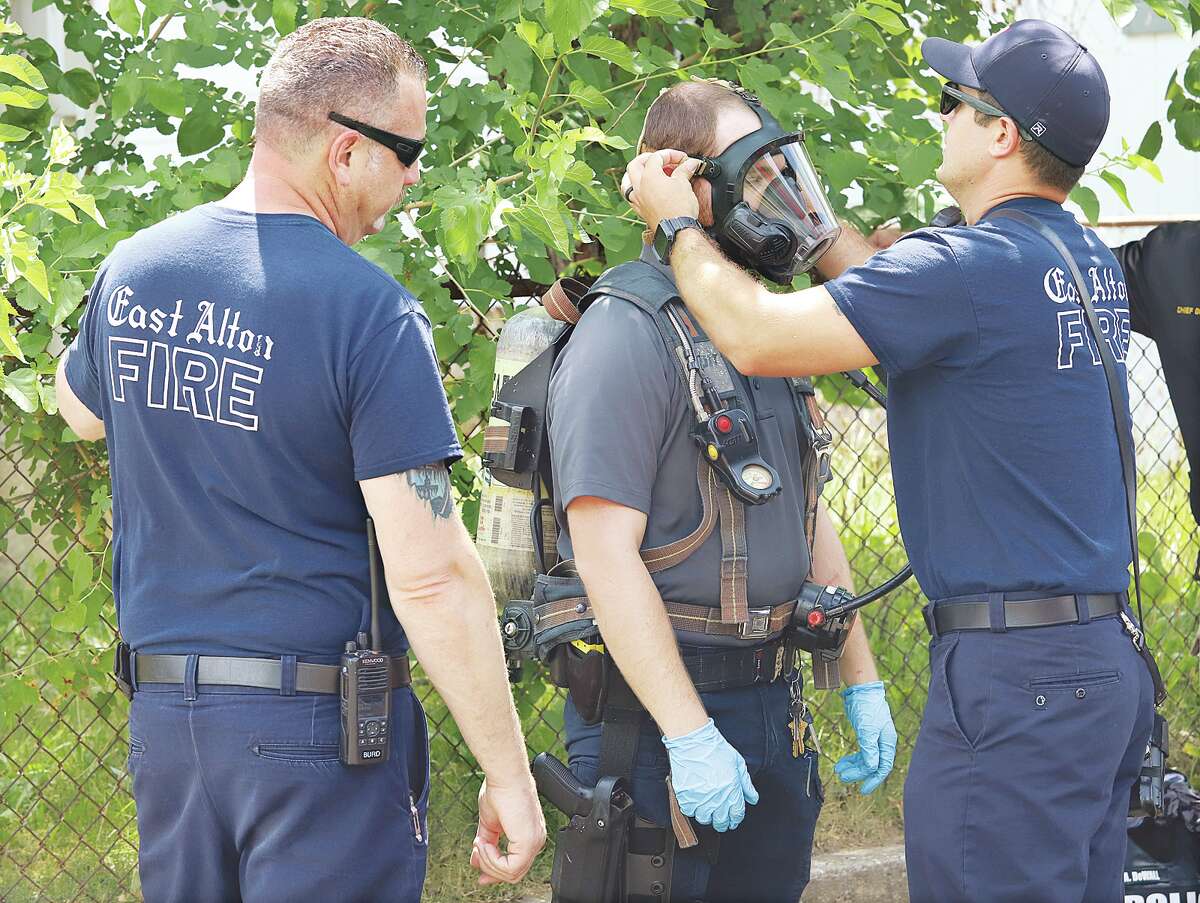 John Badman|The Telegraph East Alton firefighters on Wednesday help fit a police officer with a tank of breathable air so he could enter and round up an estimated 20 cats from an apartment.