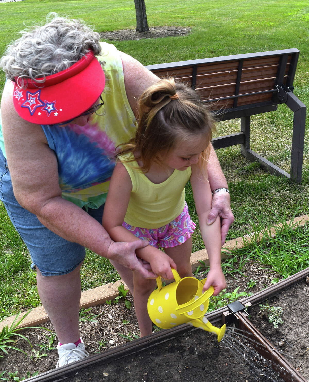 Sonya Carwile, a teacher at First Presbyterian Church Day Care Center, helps Myah Harney, 5, water plants in the Children's Community Garden. 