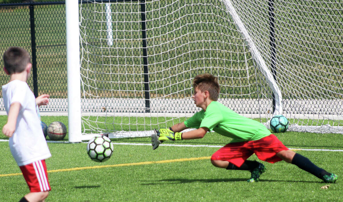 Goalie Elijah Baird dives for a shot during a drill Wednesay at the Marquette catholic High Soccer Camp at Gordon Moore Park. The camp, for elementary-school age through eighth-grade boys and girls, runs through Thursday.