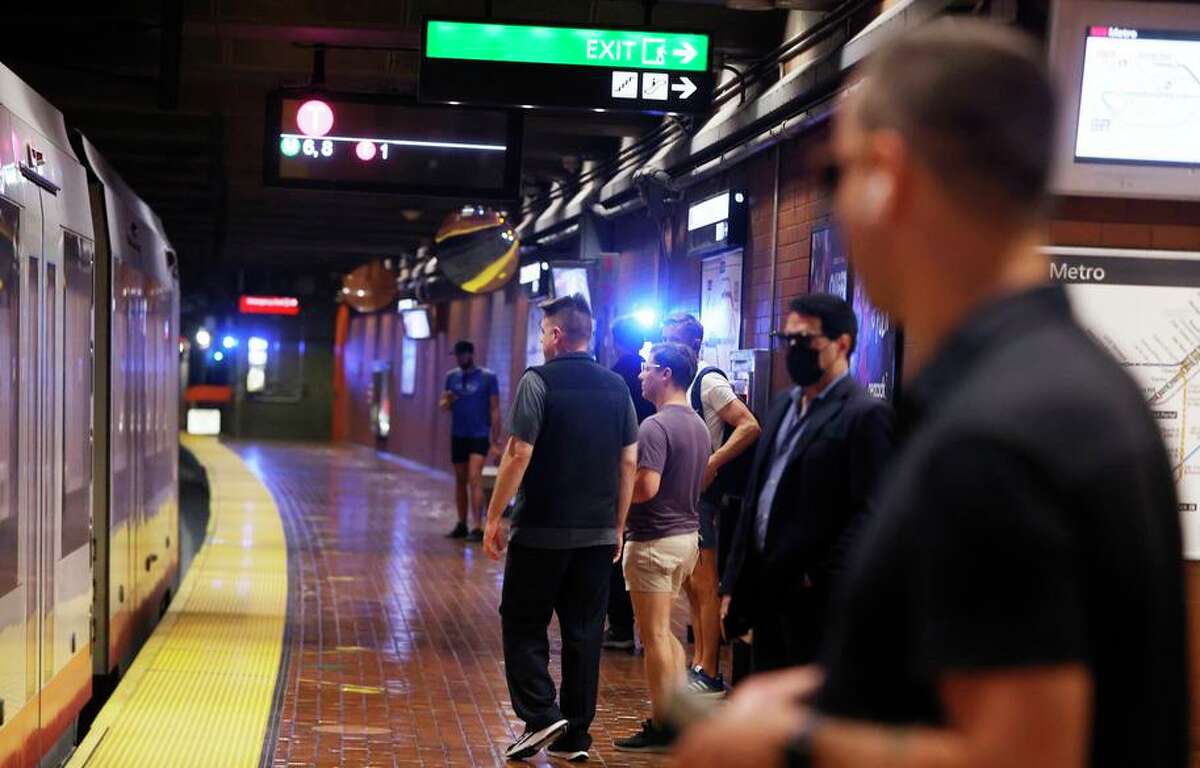 People wait to board a Muni train at Castro Street Station, where two victims received treatment after a morning shooting.