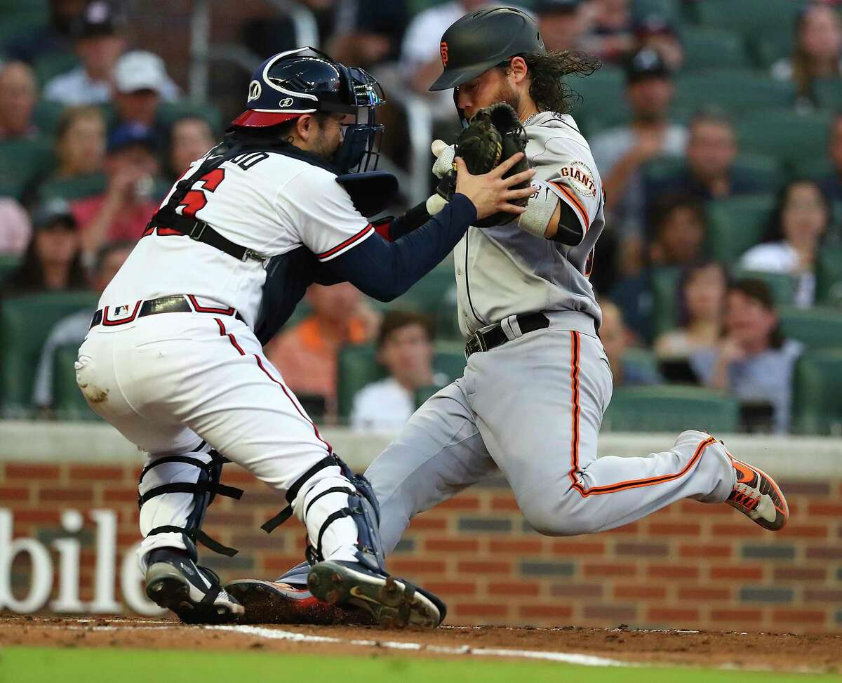 San Francisco Giants shortstop Brandon Crawford races the throw home to Atlanta Braves catcher Travis d' Arnaud during the fourth inning of a baseball game on Tuesday, June 21, 2022, in Atlanta. Crawford was called out on the play but after a review was ruled safe to take a 6-5 lead. (Curtis Compton Atlanta Journal-Constitution via AP)
