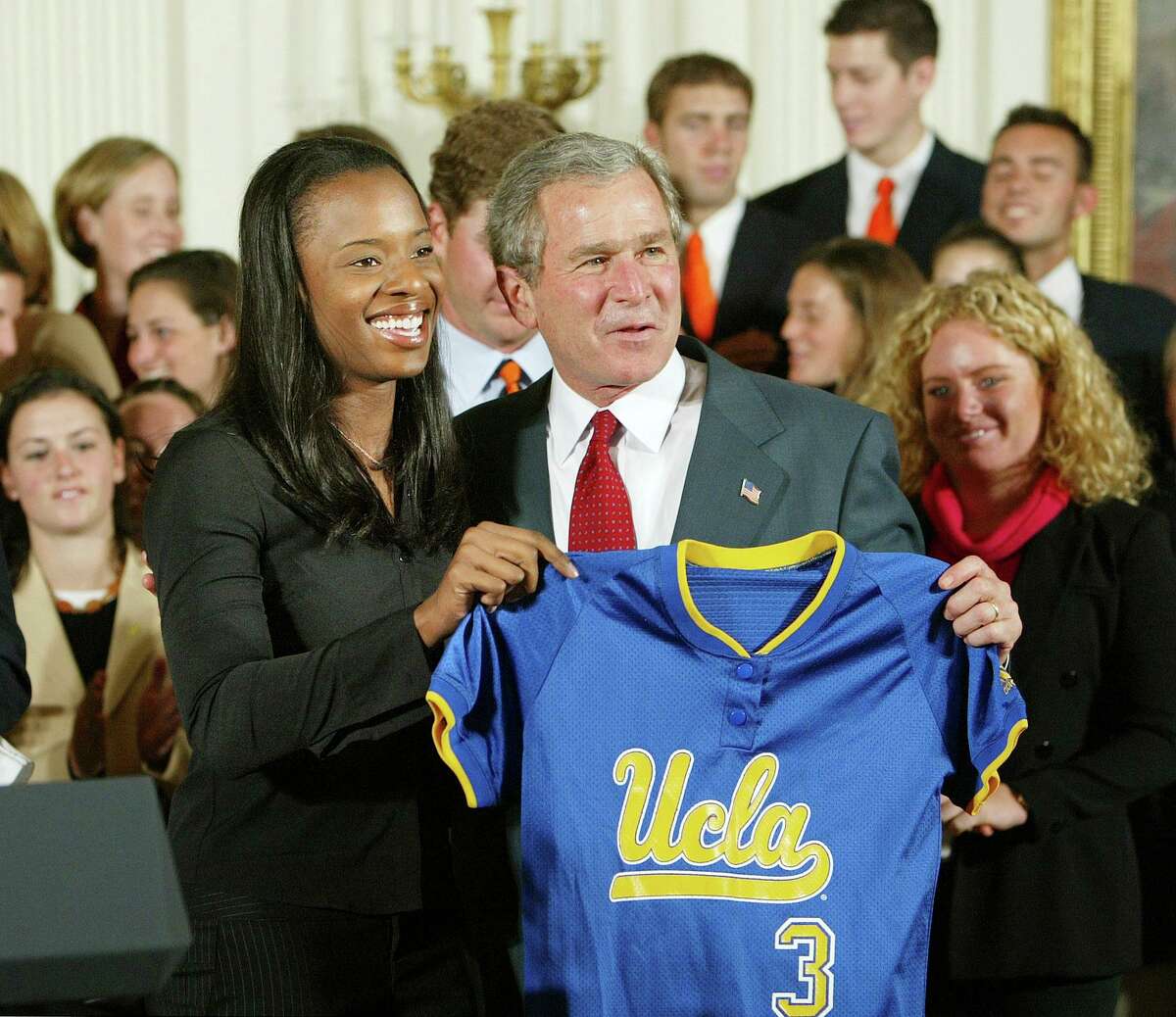FILE - President Bush holds a jersey with UCLA women's softball captain Natasha Watley as the team as he met with the reigning NCAA champions in several sports, in the East Room event at the White House in Washington, Monday, Nov. 17, 2003. Fifty years after the passage of Title IX, racial disparities still exist for women in college athletics. (AP Photo/J. Scott Applewhite, File)