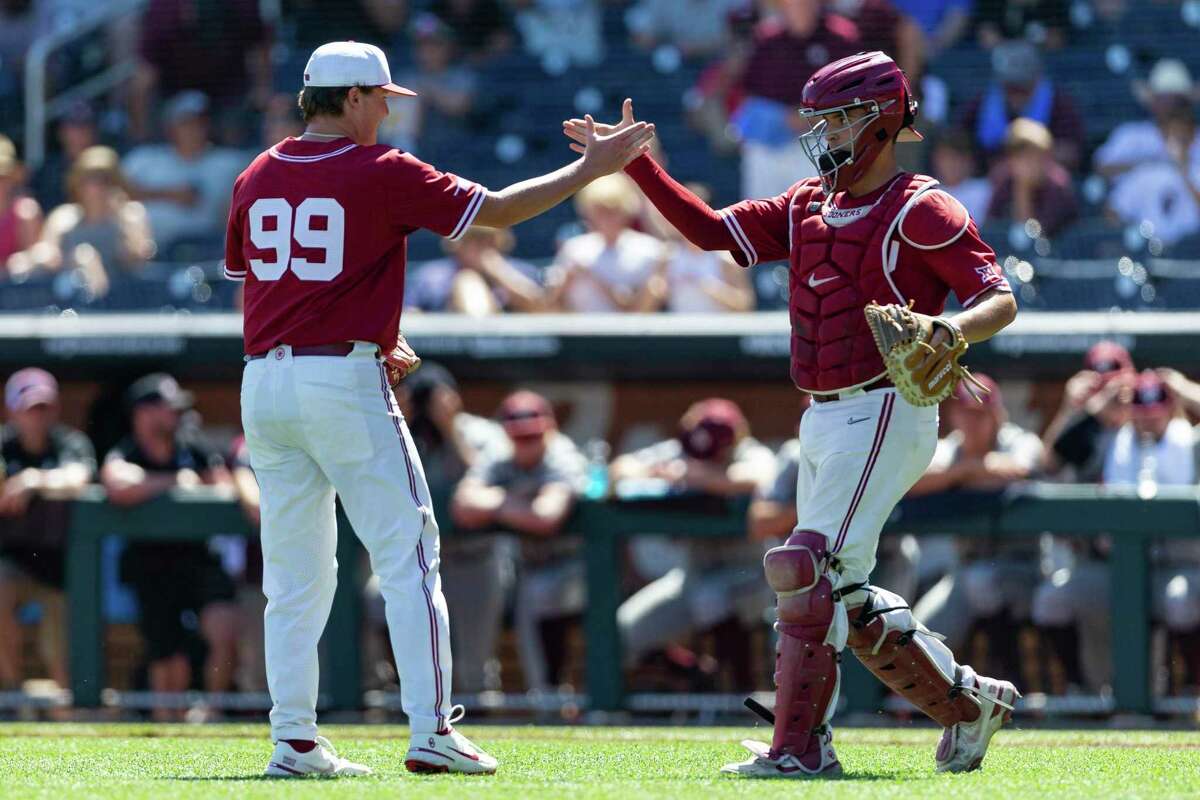 Oklahoma pitcher Trevin Michael (99) and Oklahoma catcher Jimmy Crooks (3) shake hands after their win over Texas A&M during an NCAA College World Series baseball game Wednesday, June 22, 2022, in Omaha, Neb. (AP Photo/John Peterson)