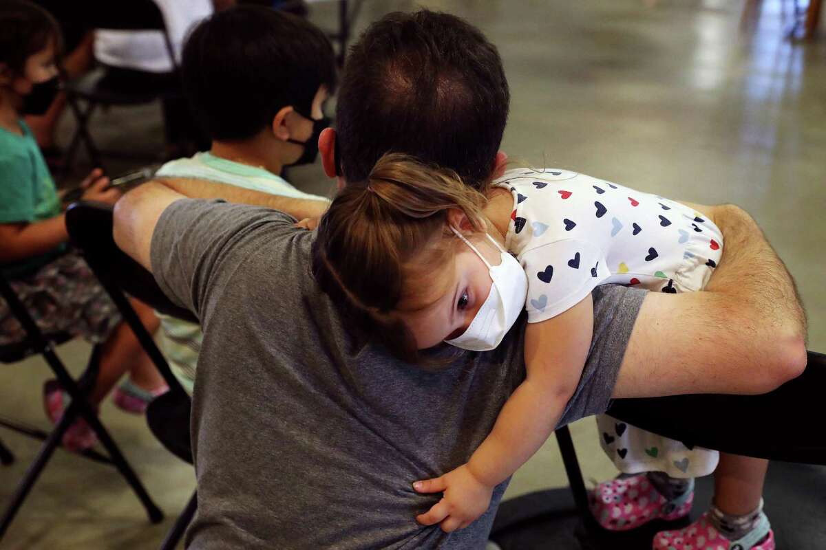 Dora Vicondoa, 2, stands on a chair to hug her father John Vicondoa of San Jose after receiving her COVID-19 vaccine at a pop-up clinic at the Santa Clara County Fairgrounds on June 21 in San Jose.