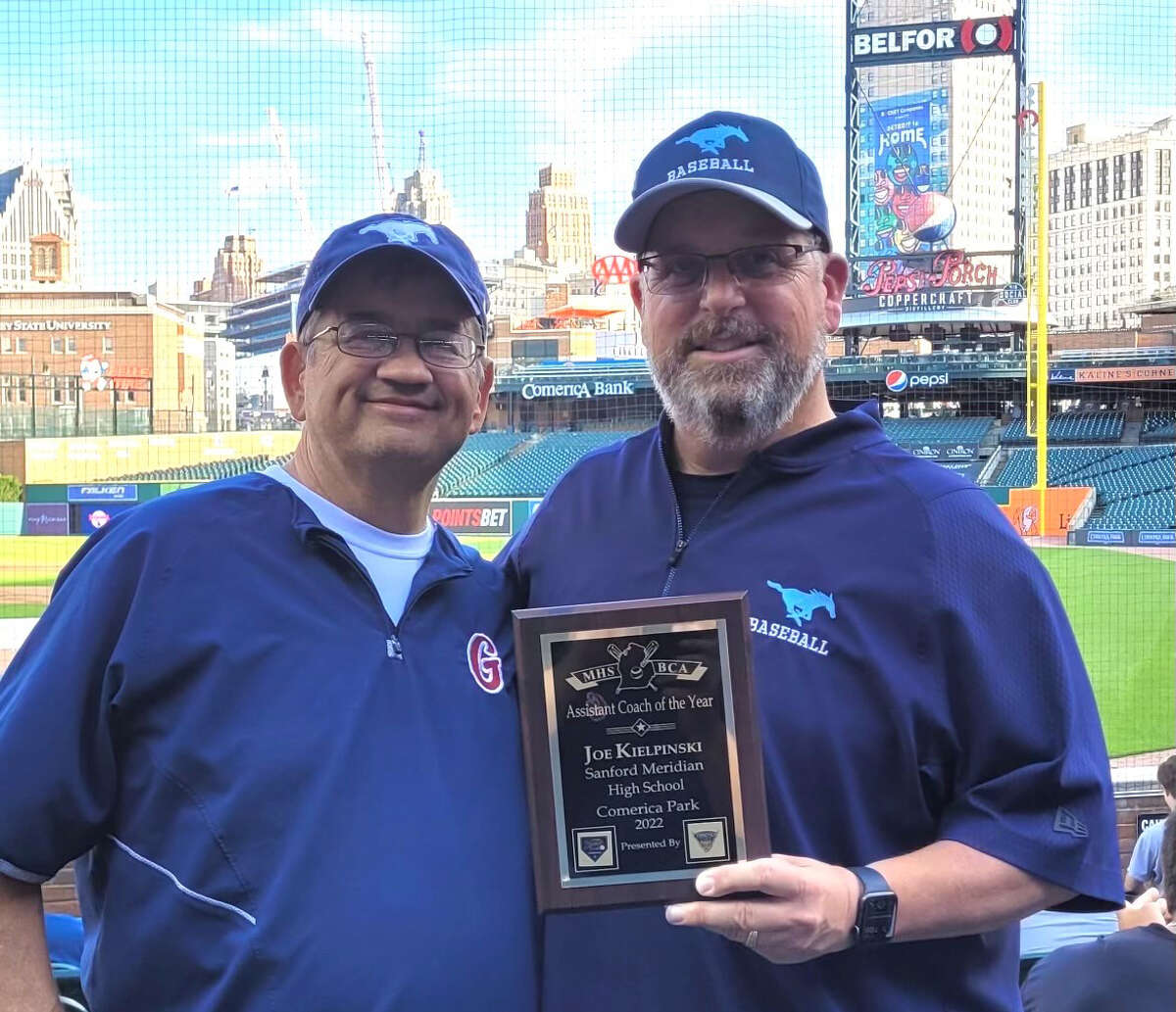 Meridian baseball assistant coach Joe Kielpinski (right) poses with longtime friend and Meridian baseball head coach Mark Novak after Kielpinski received the Assistant Coach of the Year award from the Michigan High School Baseball Coaches Association during Monday's MHSBCA all-star games at Comerica Park in Detroit.