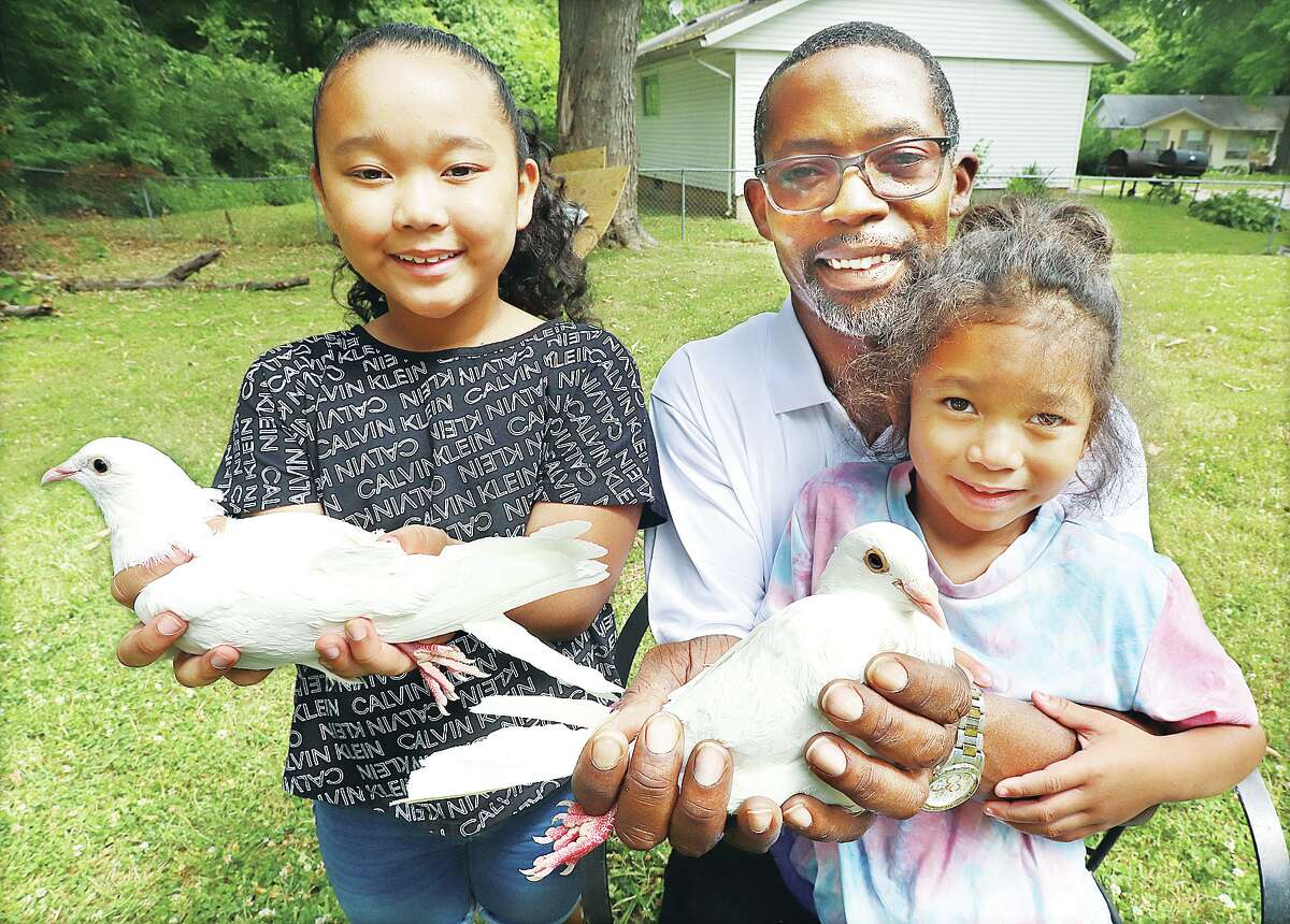 John Badman|The Telegraph Roy Williams of Godfrey shows off some of the doves he releases with his daughters, Amora, 8, left, and Mya, 6, right. The dove releases are available for a variety of events; Williams be releasing some at the dedication of the new Godfrey Splash Pad in July.