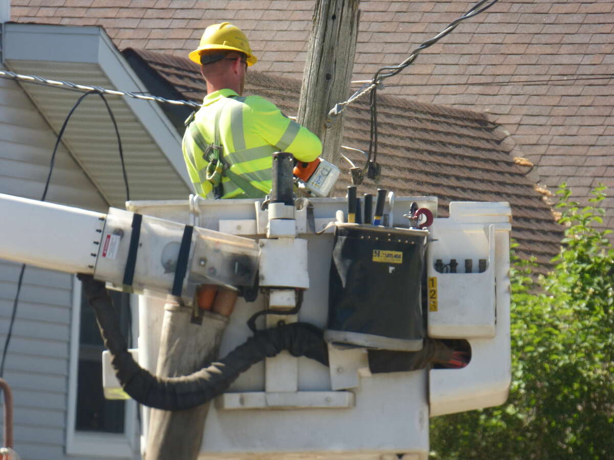 A utility worker cuts a pole that was downed Thursday morning in a collision. 