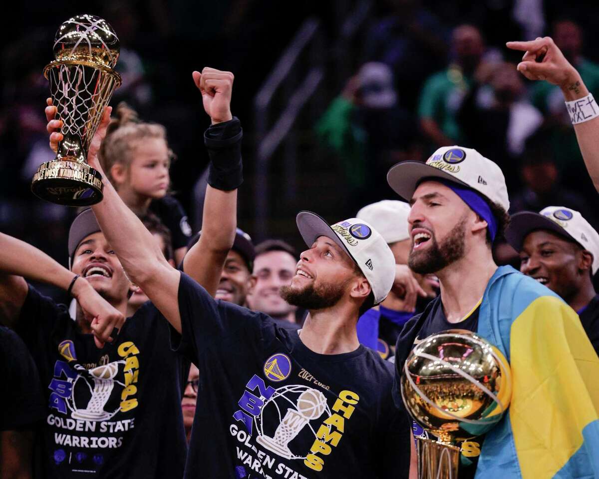 Golden State Warriors' Stephen Curry, 30, holds up the Bill Russell NBA Finals Most Valuable Player Award and Klay Thompson, 11, holds the Larry O’Brien Championship Trophy after defeating the Boston Celtics 103 to 90 in Game 6 of the NBA Finals at TD Garden in Boston, Mass., on Thursday, June 16, 2022.