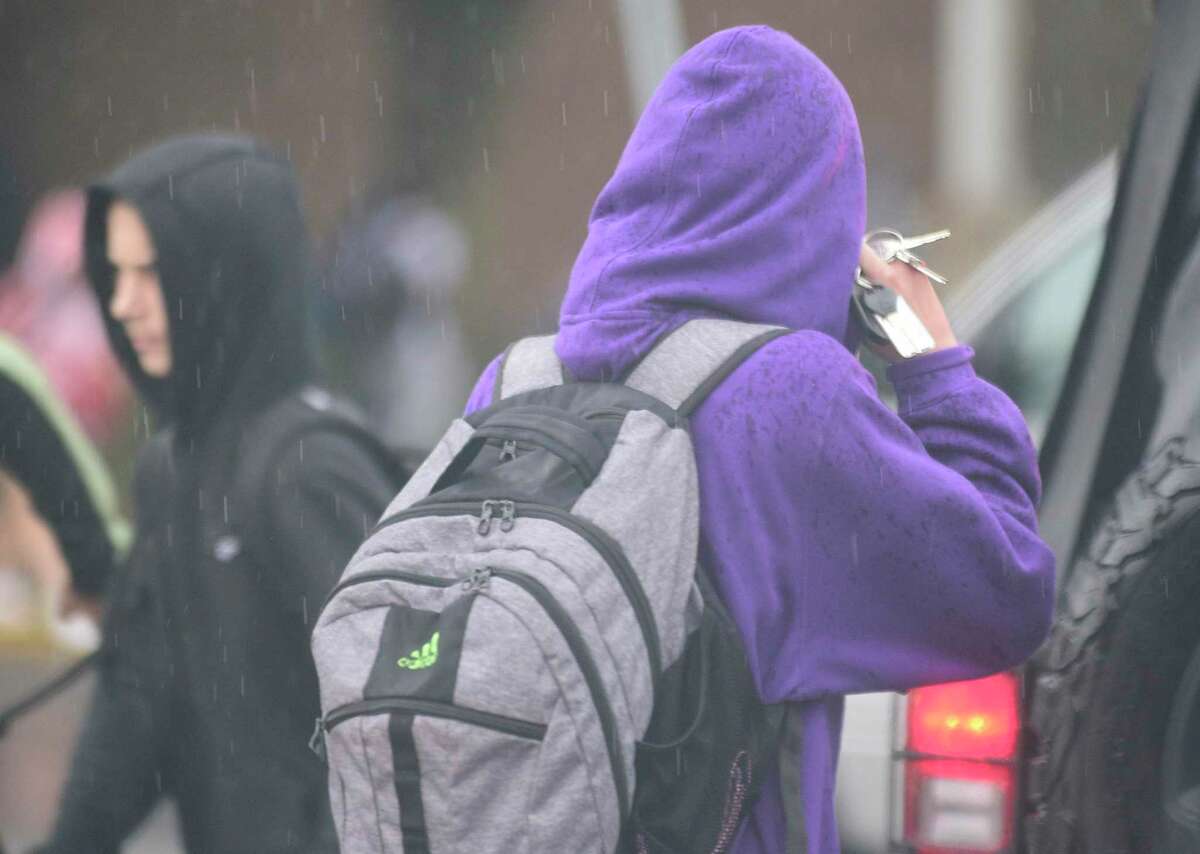 A Westhill student talks on a cell phone while walking in the rain at school dismissal on Sept. 25, 2018 in Stamford, Connecticut.