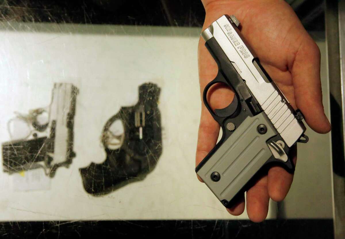 A weapons shop clerk displays a small handgun.