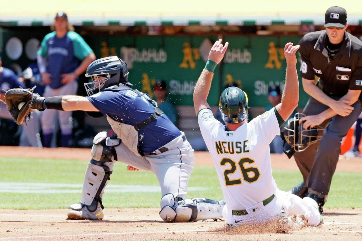 Oakland Athletics third baseman Sheldon Neuse (26) scores against Seattle Mariners catcher Luis Torrens (22) in the first inning during an MLB game at RingCentral Coliseum, Thursday, June 23, 2022, in Oakland, Calif. Neuse scored from second base after a single by the A’s Christian Bethancourt.