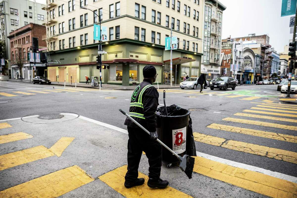 An Urban Alchemy street ambassador sweeps near the corner of Turk and Jones streets in the Tenderloin. Some San Francisco supervisors say there are more ambassadors than needed.
