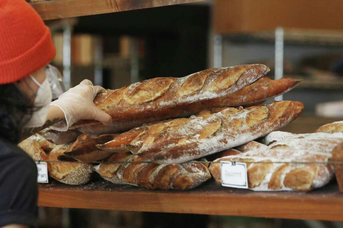 Renee Robleda selects a baguette for a customer at Jane the Bakery in San Francisco.