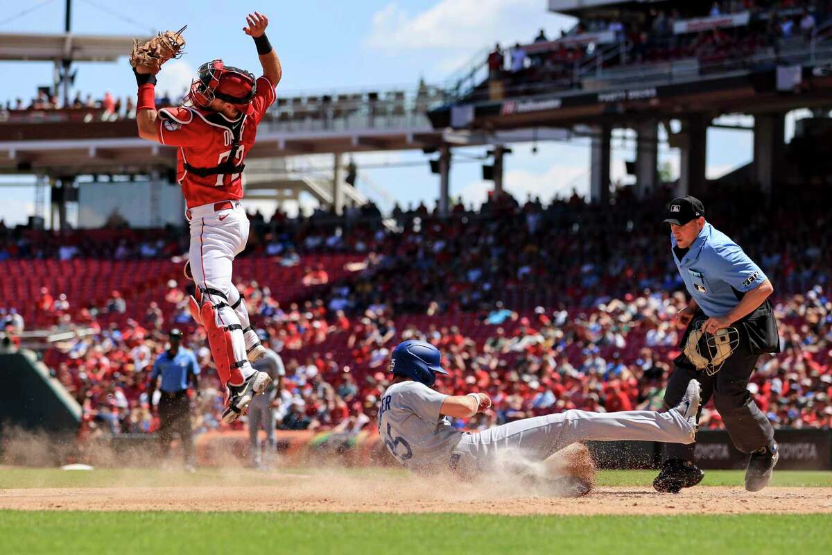 The Dodgers’ Cody Bellinger scores on a hit by Freddie Freeman as the Reds’ Chris Okey leaps to field the throw.