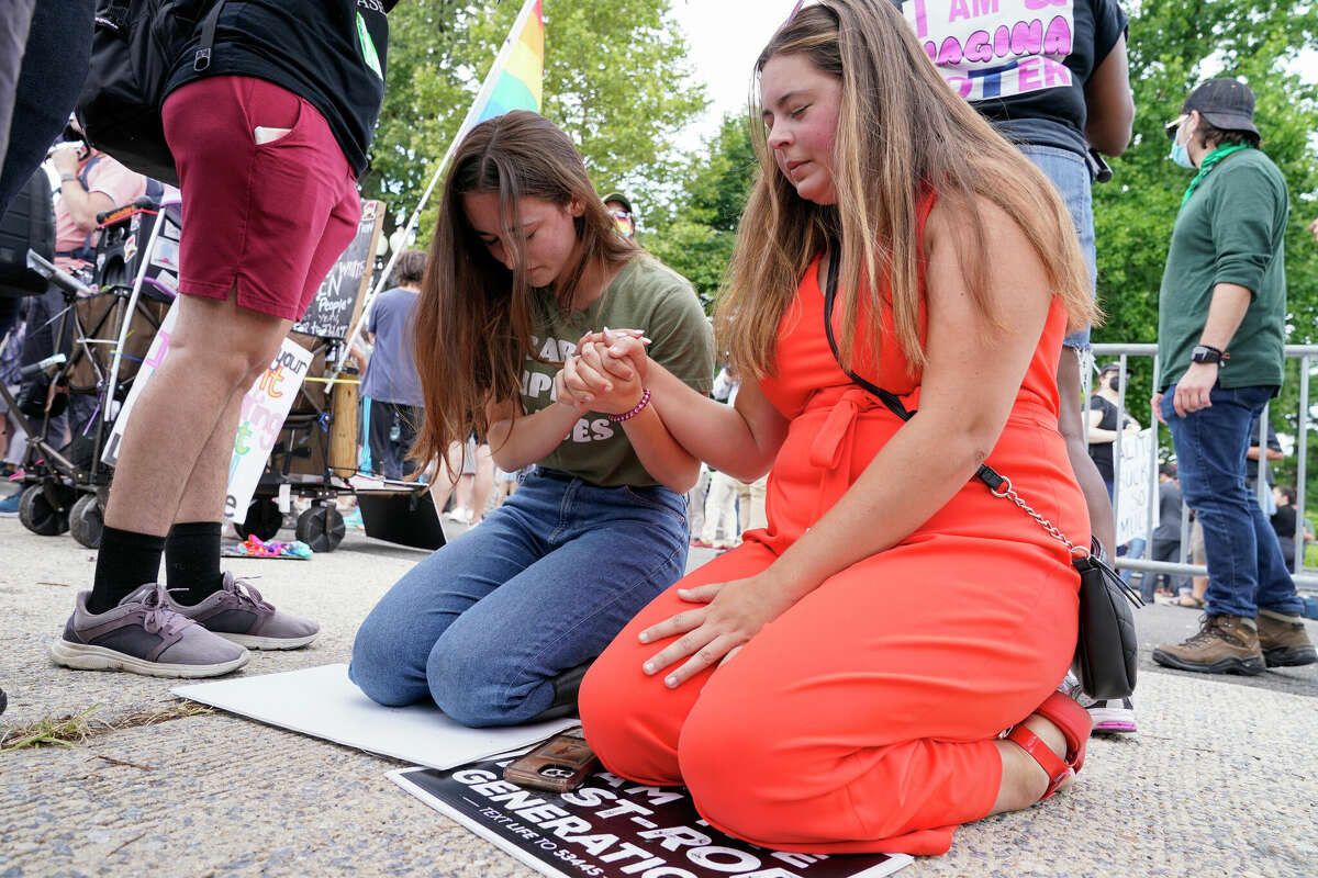 Anti-abortion activists Maggie Donica, 21, right, and Grace Rykaczewski, 21, left, pray following the Supreme Court's decision to overturn Roe v. Wade, the federally protected right to abortion, in Washington on Friday, June 24, 2022.