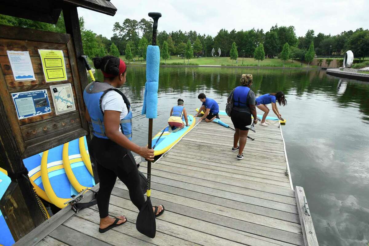 Women from Black Women who Kayak get equipped with paddle boards at the Riva Row Boat House Saturday, June 18, 2022, in The Woodlands, Texas.