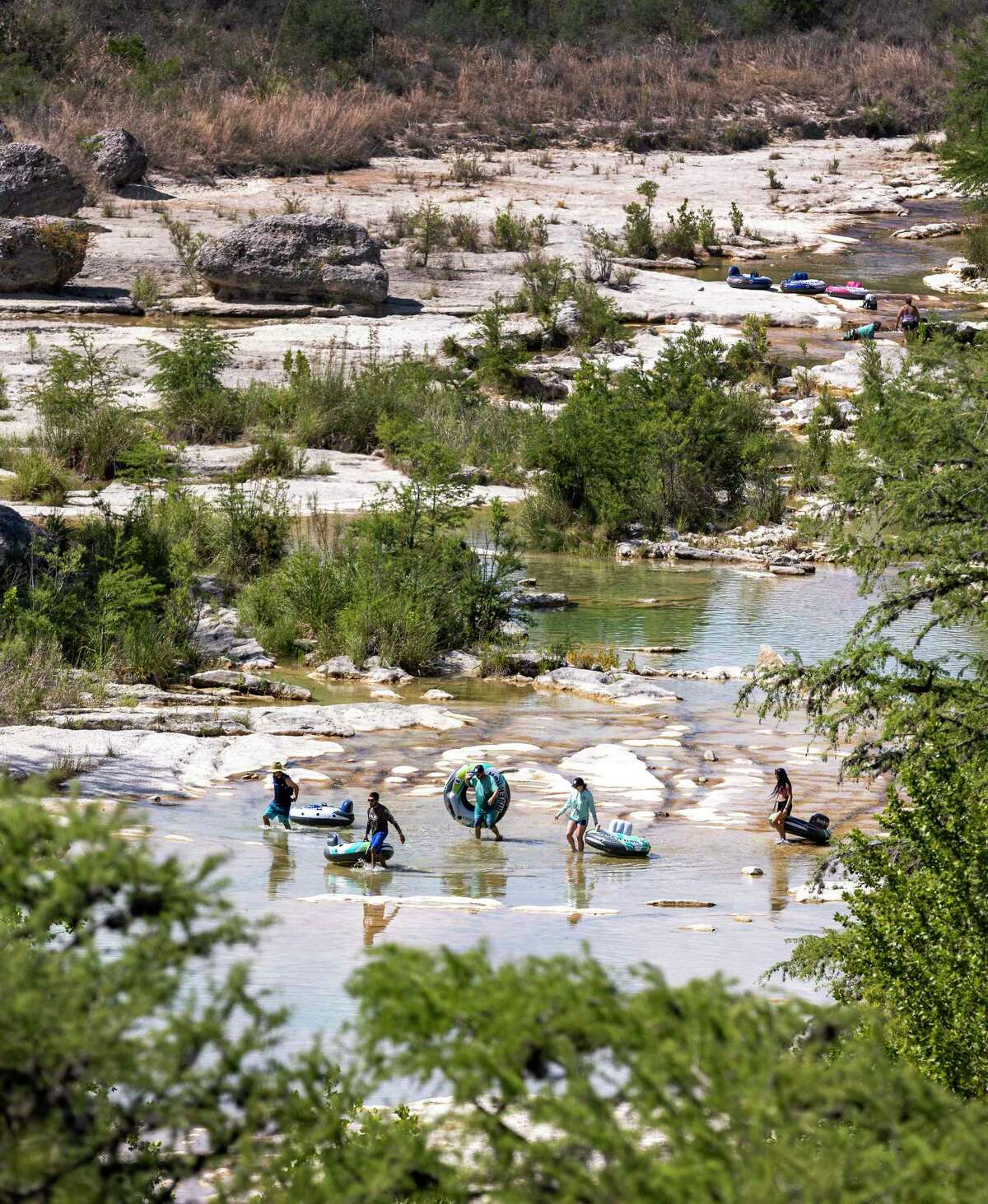 People carry inner tubes on June 23 along a nearly dry Frio River in Garner State Park. The U.S. Geological Survey’s river gauge in Concan measured zero flow in the river that day.