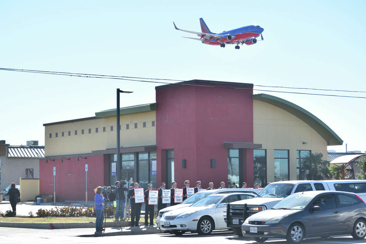 A Southwest Airlines plane flies over protesting Southwest Airlines pilots at Dallas Love Field.