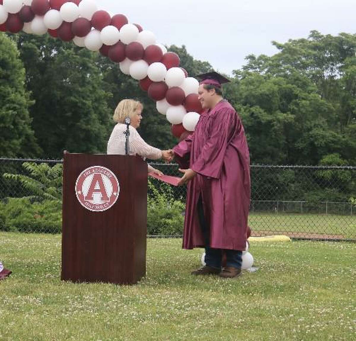 Academy teacher Kelly Graham presents graduating senior Nathan Visconti with his diploma at the school’s commencement ceremony on June 16, 2022.