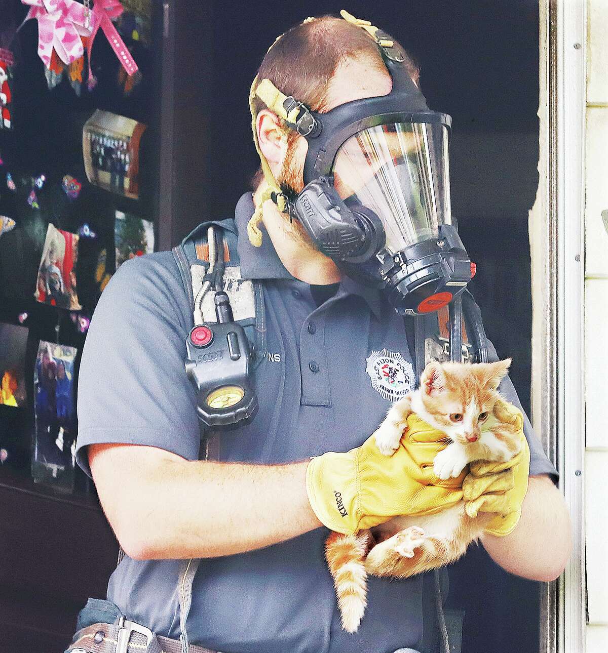 John Badman|The Telegraph An East Alton Police officer, wearing a fire department tank of breathable air, carries out one of about 20 cats from a duplex Wednesday in the 100 block of Ohio Street.