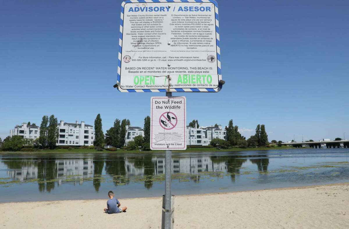 Lucas of San Mateo sits on Lakeshore Park beach next to an advisory stating that water levels are tested weekly for bacteria. The beach was listed by the nonprofit Heal the Bay as one of the most polluted in California.